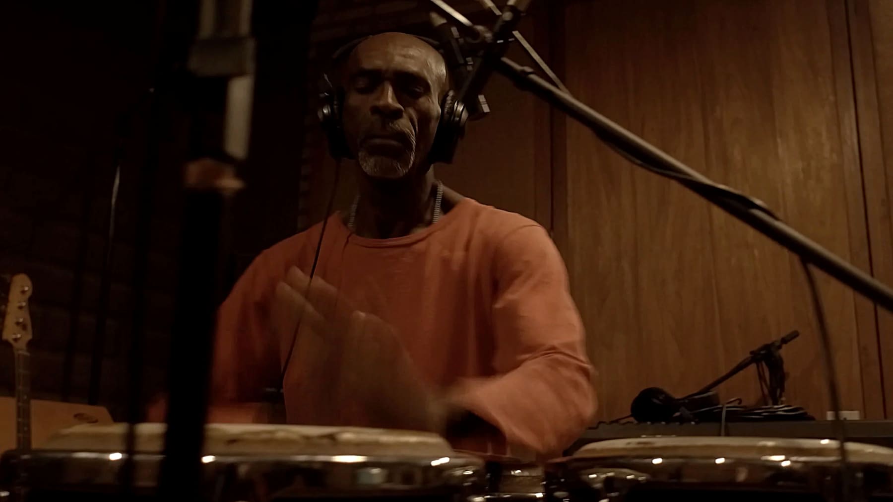 Gabi Guedes at the congas, headphones on, eyes closed